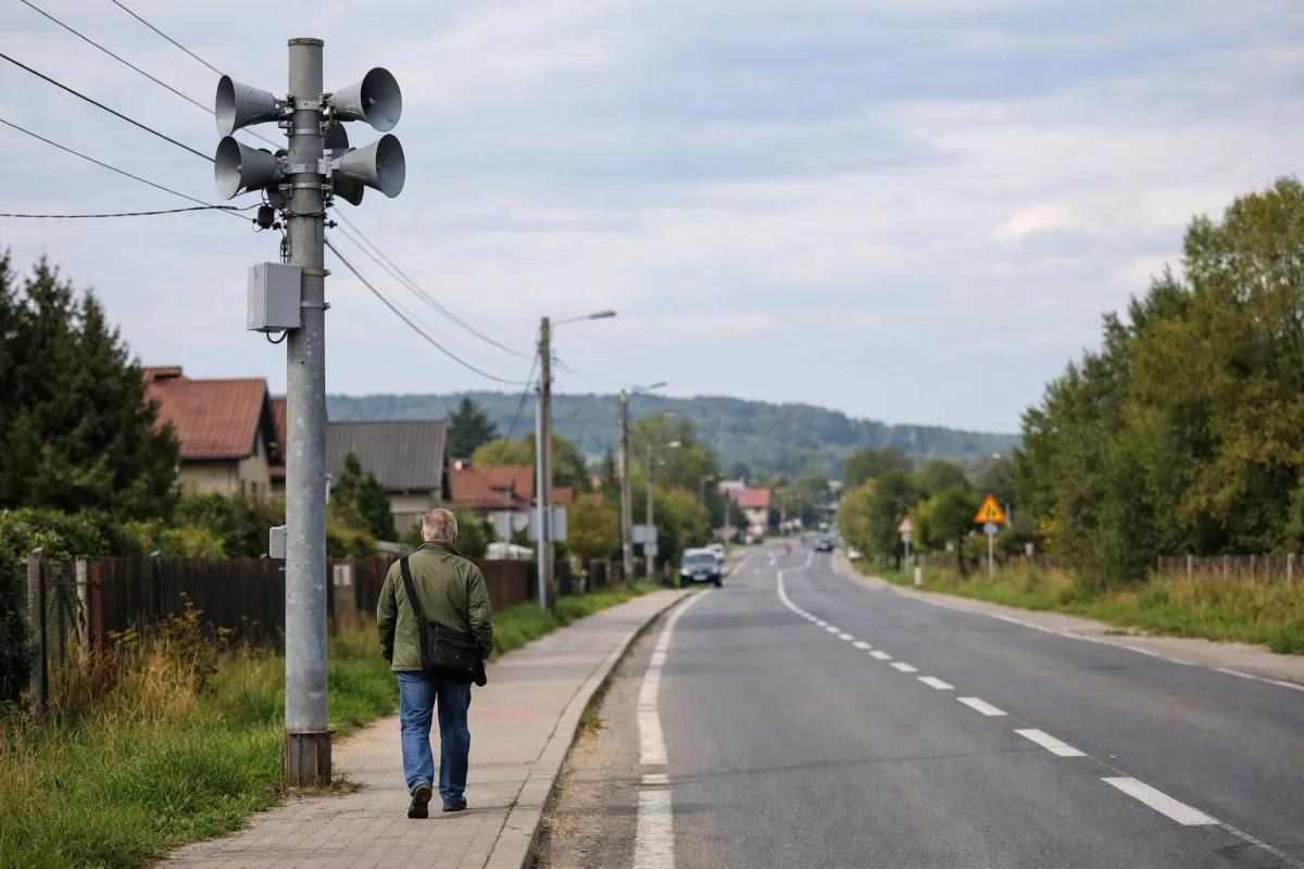 Słup z głośnikiem syreny alarmowej przy zwykłej ulicy wiejskiej w Małopolsce.